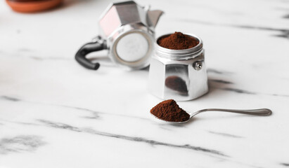 A spoon with coffee, Italian coffee maker Moka with coffee on a marble background - a process of making coffee