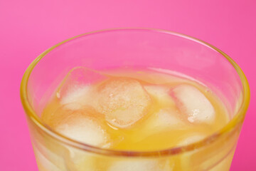 Glass of orange soda on pink background, close up