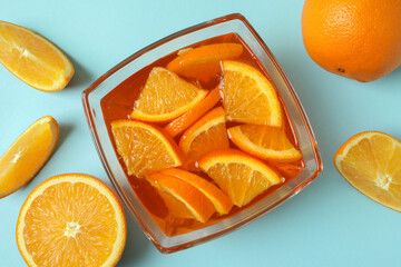 Fototapeta na wymiar Bowl of orange jelly with orange slices on blue background