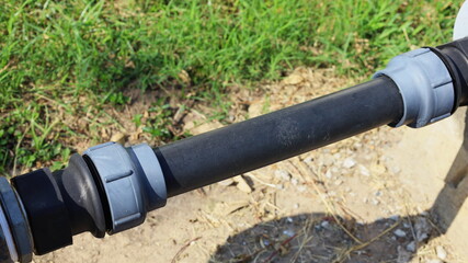 Couplings and PE pipes. Compression adapter for PE pipes of water supply pipeline system. On a background of green grass and outdoor pipe shadows. Choose a subject and focus closer.