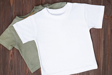 White tshirt mockup on brown wooden background. Template, flat lay. Clothes mockup, kid shirt