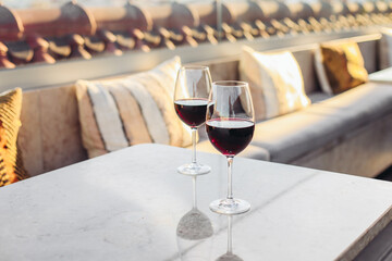 Two glasses of red wine on a rooftop bar terrace, relaxed atmosphere, romantic evening