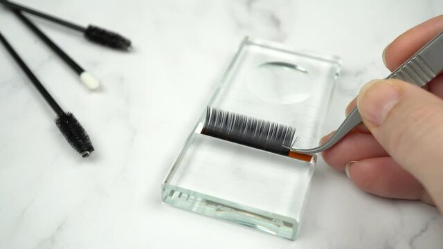 Volume lash extensions set up. Lash artist demonstrates how to make 4D Russian volume fans. Real time motion footage in professional salon setting with beauty tools, products and equipment.