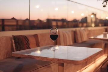 A glass of red wine on a fancy restaurant, evening sunset light on a terrace