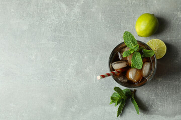 Glass of Cuba Libre and ingredients on gray background