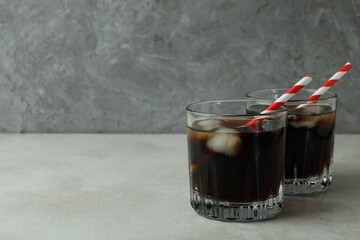 Glasses of cola on white textured table against gray background