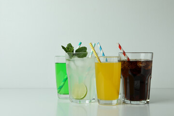 Glasses of different soda on white background