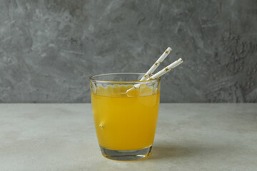 Glass of orange soda on white textured table against gray background