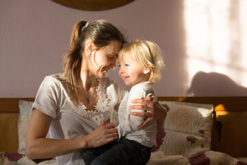 Mom and child, having fun together, reading book and eating croissant