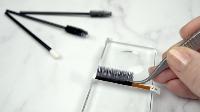 Volume lash extensions set up. Lash artist demonstrates how to make 5D Russian volume fans. Real time motion footage in professional salon setting with beauty tools, products and equipment.