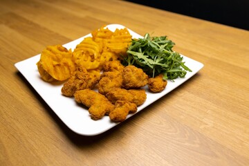 Chicken nuggets with salad on table closeup
