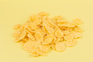 Pile of yellow cornflakes on yellow  background