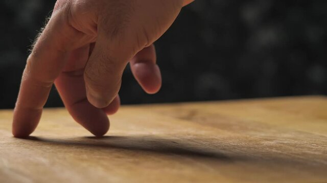 Men hand making standing person with fingers, a walking man. The fingers are walking like a figure on a wooden table on a black background.