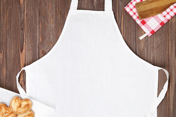 White apron template on brown wooden table with cookies. Kitchen, cooking clothing mock up