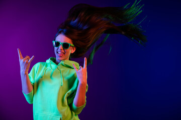 Photo of charming crazy young woman make rock sings stick out tongue fly hair isolated on neon color background