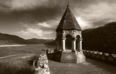 old fortress remains on the river bank in mountains in black and white 