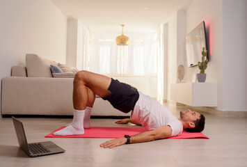 Sporty man doing bodyweight glute floor bridge pose at home