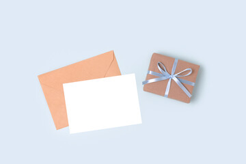 Envelope, empty paper card mockup and gift box on a blue pastel background. Present and letter for Fathers Day.