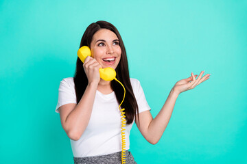 Photo of young cheerful woman happy positive smile call talk telephone look empty space isolated over turquoise color background