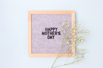 Happy Mothers day. Letter board and gypsophila flower on a blue pastel background. Festive concept.