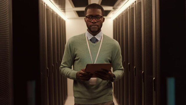 Lockdown of young African male IT technician with digital tablet in hands going out of server room