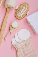 Ecological set of wooden body accessories on a pink background Massage brush for health eco direction Towel and reusable cotton pads for facial care