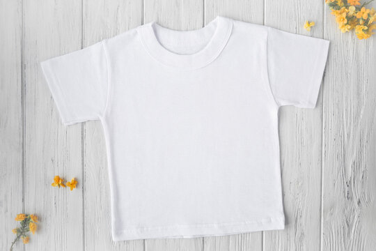 Spring, summer white tshirt mockup with yellow flowers on wooden background, top view
