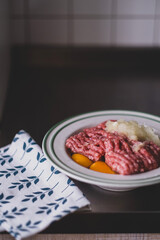 minced pork, raw chicken eggs and onions in a white plate on the kitchen table. ingredients for cooking cutlets, meat pie, meatballs and meatballs. Nutritious hearty lunch, protein food, farm products