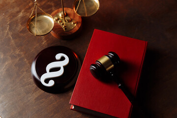 Paragraph symbol in courtroom and judge gavel on a law book.