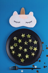 Kiwi slices in the shape of stars on a plate as a product to restore healthy sleep on a blue background. 