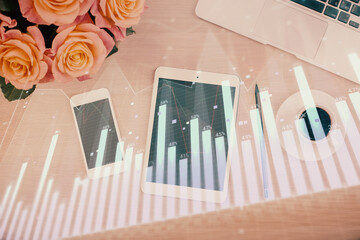 Double exposure of forex graph hologram over desktop with phone. Top view. Mobile trade platform concept.