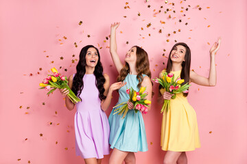 Photo of impressed nice long hairdo ladies hold flowers look empty space wear pastel dress isolated on pink color background