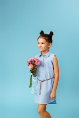 adorable smiling little girl holding bouquet of roses isolated on blue studio background. child...