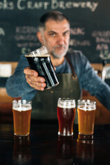 barman standing in bar. He is serving craft beer