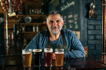 barman standing in bar. He is serving craft beer