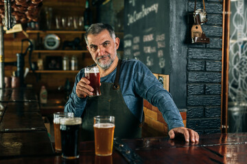 barman standing in bar. He is serving craft beer