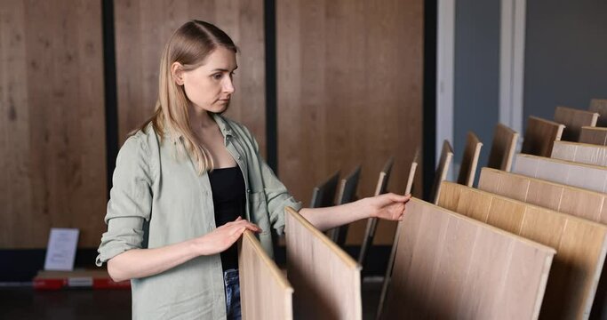 woman choosing laminate floor design from samples in flooring shop
