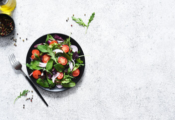 Mix salad with tomatoes, onions and olive oil in a black plate. Detox menu. The keto diet.