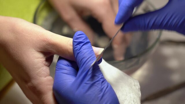 Closeup view 4k video footage of professional manicurist doing modern trendy manicure in cosmetology beauty spa studio. Nailmaster filing nails of client with file making beautiful natural shape