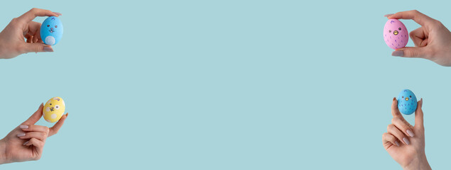 Easter decoration. Festive ornament. Holiday traditional symbol. Set of 4 blue pink yellow color painted egg with bunny chicken design in female hand isolated on light copy space background.