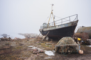 Old fishing boat stands to be repaired on a foggy morning. Estonia - 417811097
