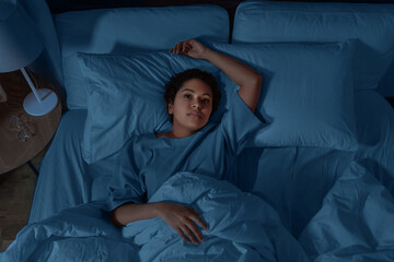 people, bedtime and rest concept - sleepless african american woman lying in bed at night