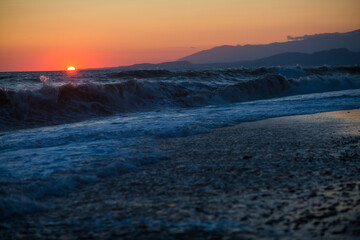 beautiful sunset by the sea with strong waves