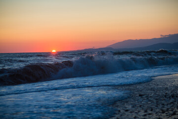 beautiful sunset by the sea with strong waves