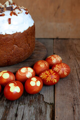 Easter cake and colored eggs. Rustic food on a wooden table. Egg colored with onion peel. Clover and dill leaves pattern. Classic food for the Easter holiday