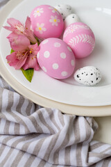 Obraz na płótnie Canvas Easter menu. Holiday meal. Festive food art. Pink white painted egg with polka dot modern floral ornament decorated with flower served in plate on striped tablecloth.