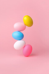 colorful easter eggs balancing over pink background