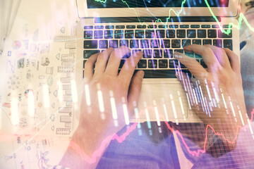 Double exposure of man's hands typing over laptop keyboard and forex chart hologram drawing. Top view. Financial markets concept.