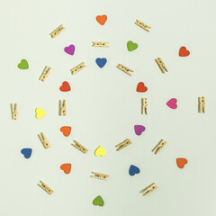 Fototapeta na wymiar Clothespins and red, blue, green, yellow, purple and orange hearts in concentric circles.Flat lay on white background