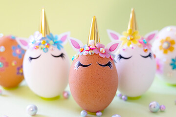 brown and white Easter eggs decorated in the form of unicorns on a green and yellow background, a minimal creative concept of a happy Easter